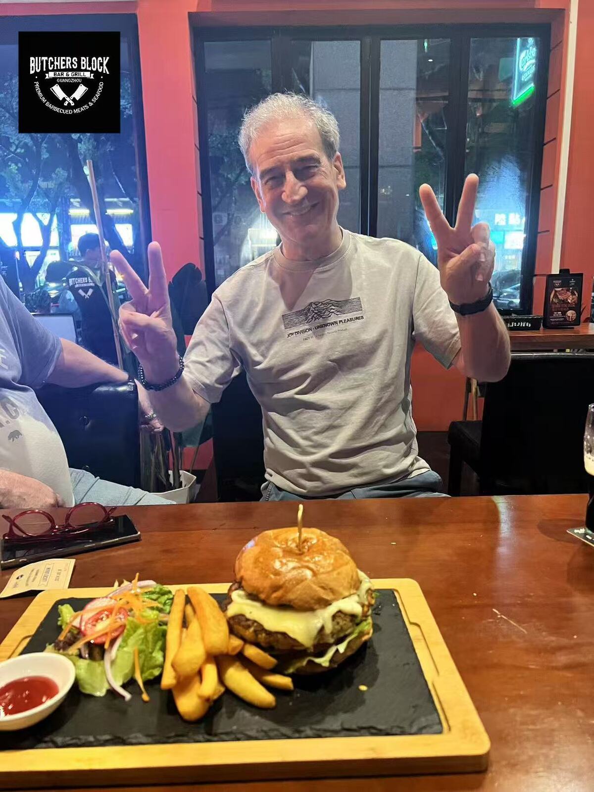 Delicious gourmet burger with melted cheese, fries, and fresh salad at Butchers Block Bar & Grill in Guangzhou.