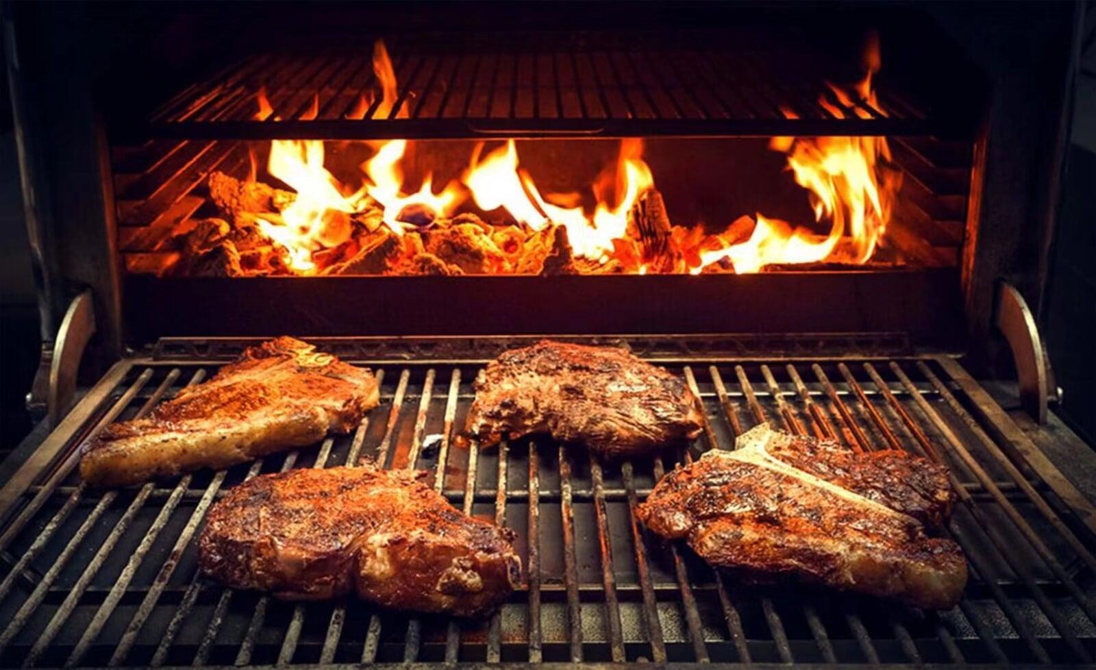 Flame-grilled steaks cooking over an open fire at Butchers Block Bar & Grill, known for premium barbecued meats in Guangzhou.