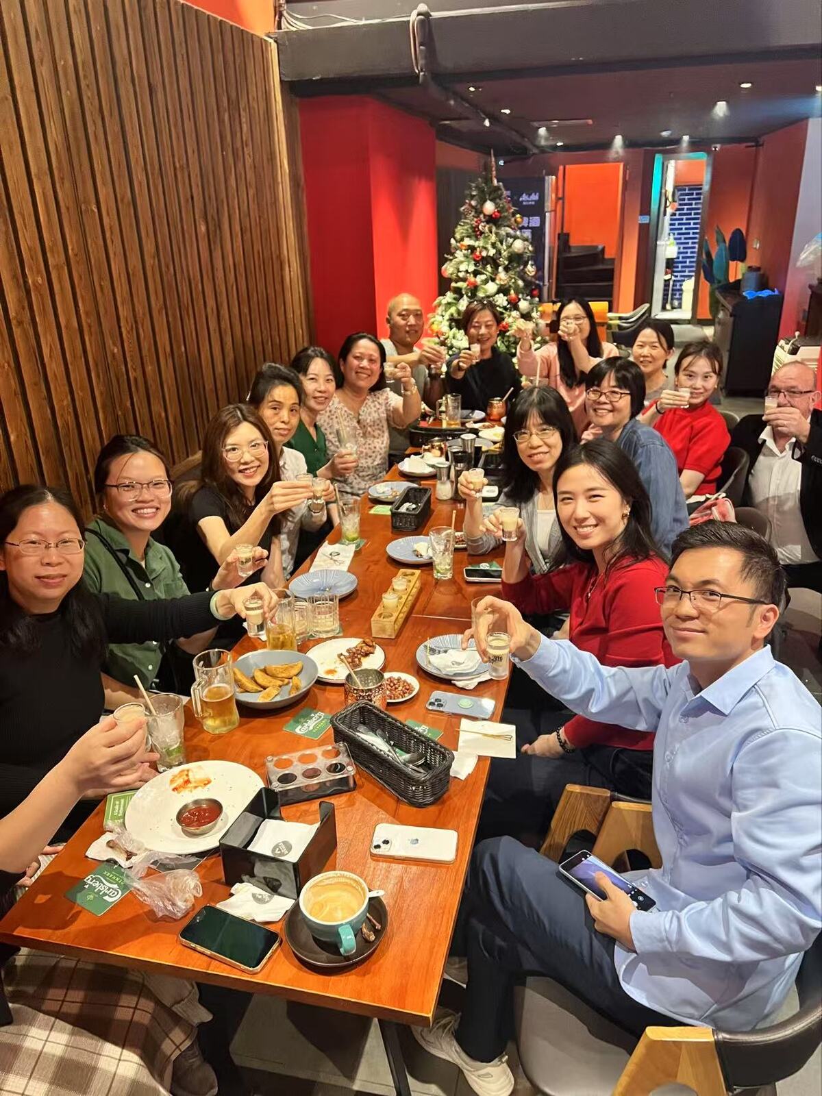 Group of people enjoying a dinner gathering at a restaurant in Guangzhou, raising glasses for a toast.