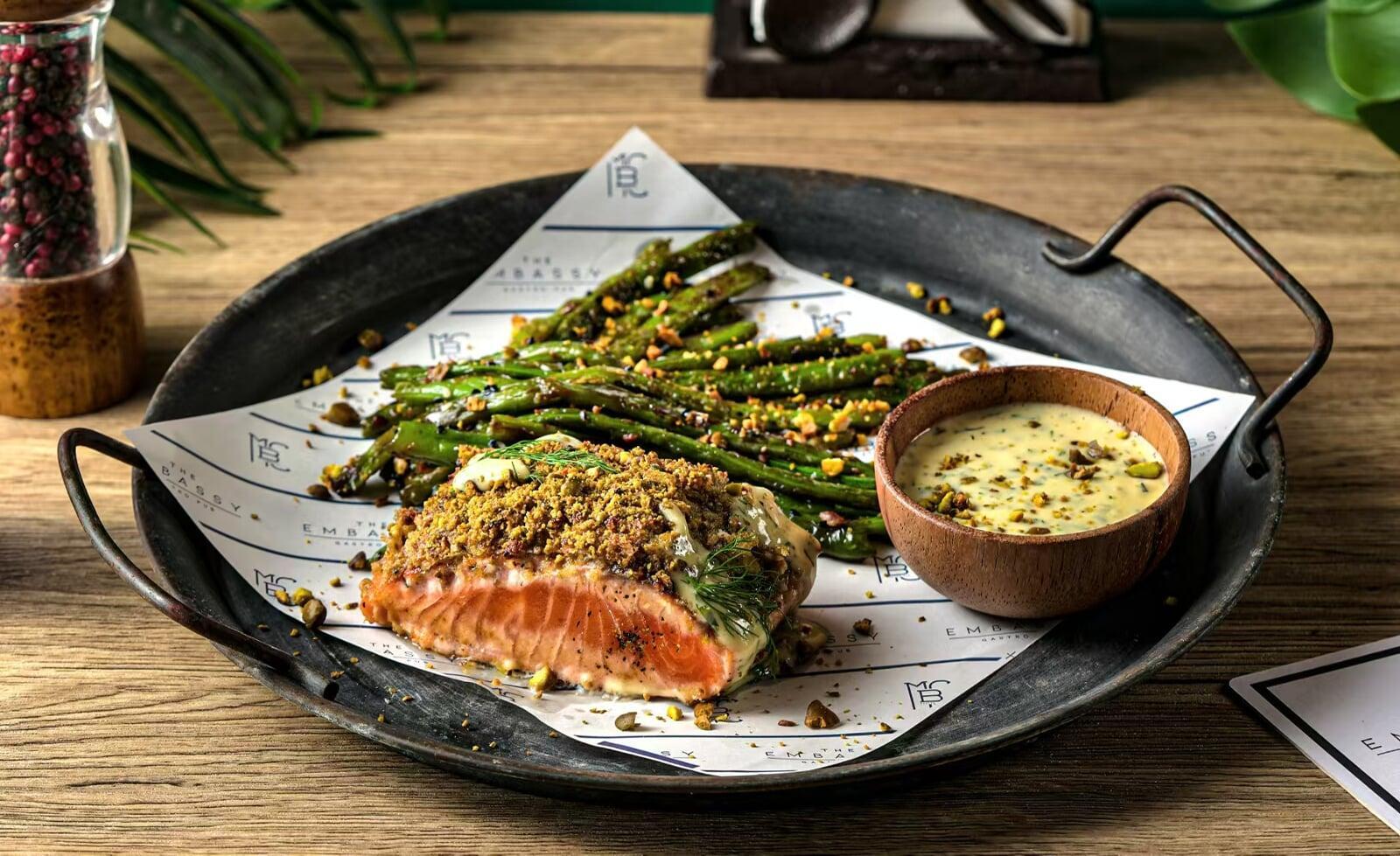 Gourmet pistachio-crusted salmon with roasted asparagus and creamy sauce, plated beautifully at The Embassy Bistro in Guangzhou.