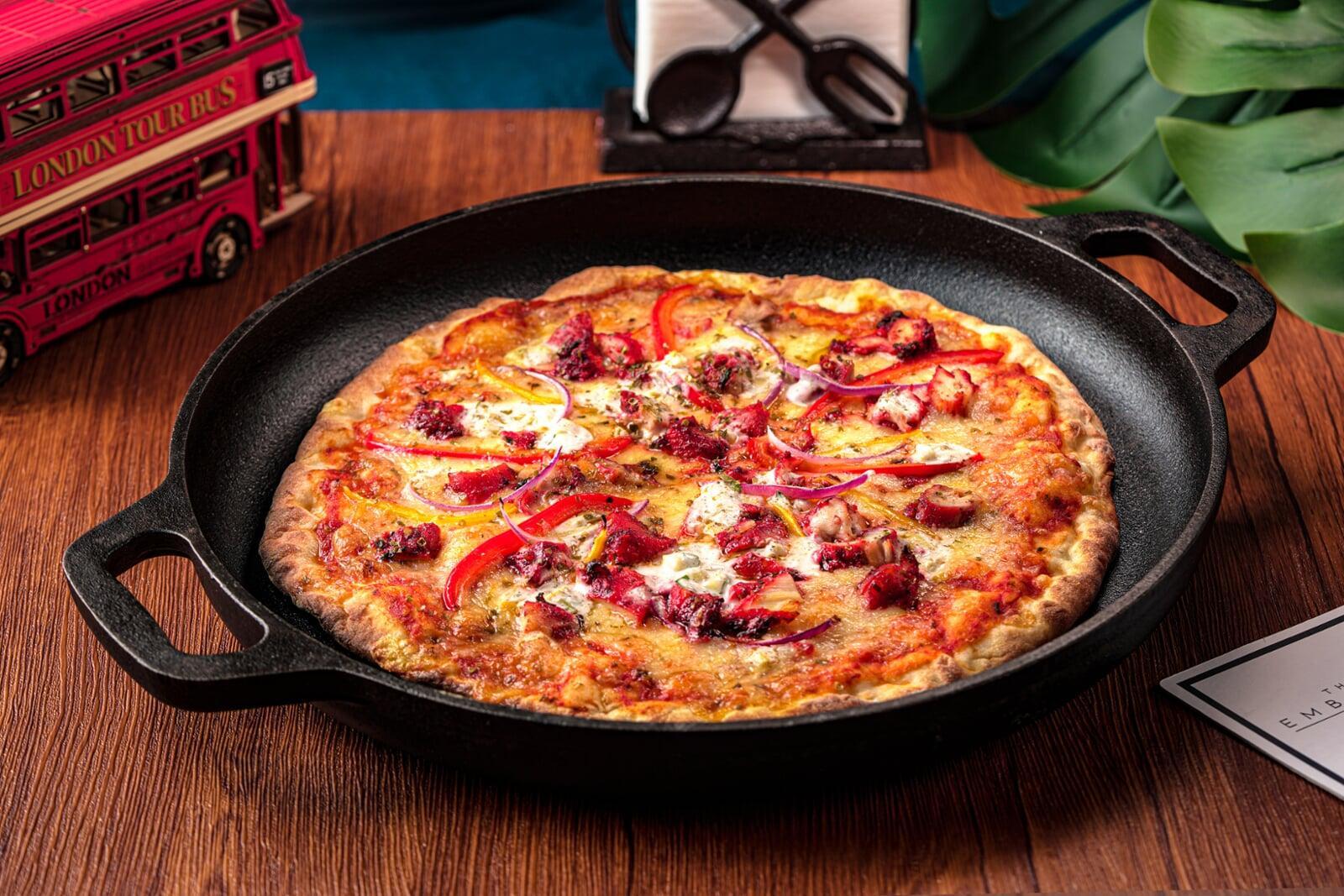 Delicious tandoori chicken pizza with red onions and melted cheese, served in a skillet at The Embassy Bistro in Guangzhou.